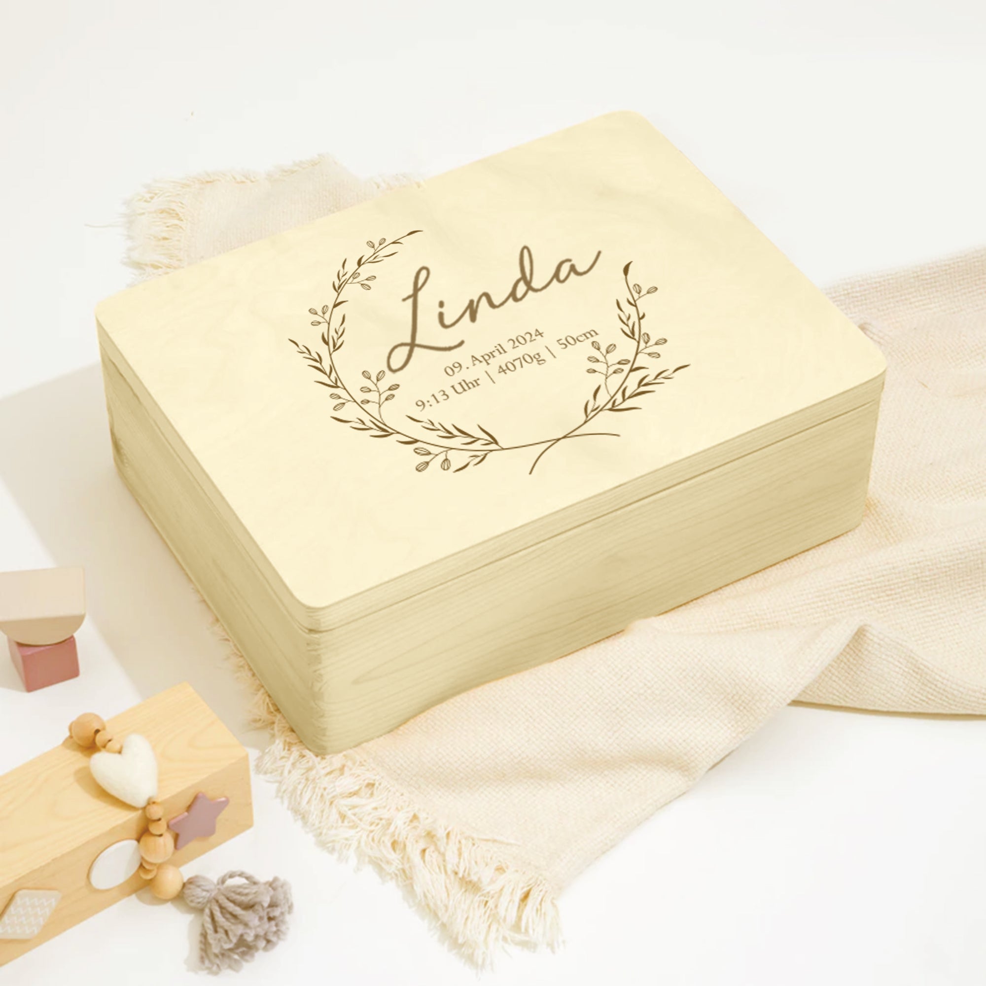 Erinnerungskiste Baby mit Name Linda, liebevoll inszeniert mit Spielzeug und Decke