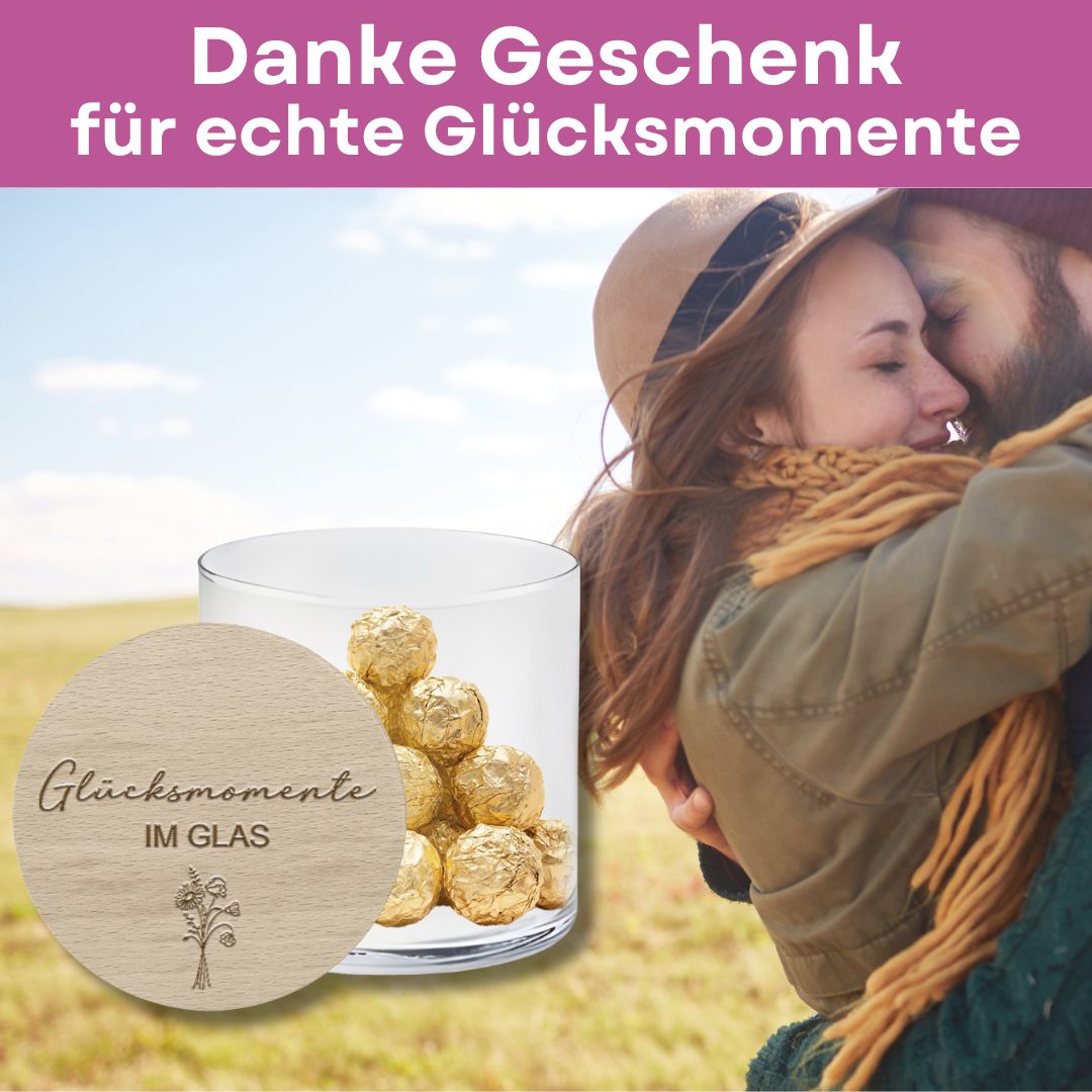 Emotionales Dankeschön-Geschenk: Vorratsglas mit Gravur „Glücksmomente im Glas“ und goldenen Pralinen vor einer innigen Umarmung