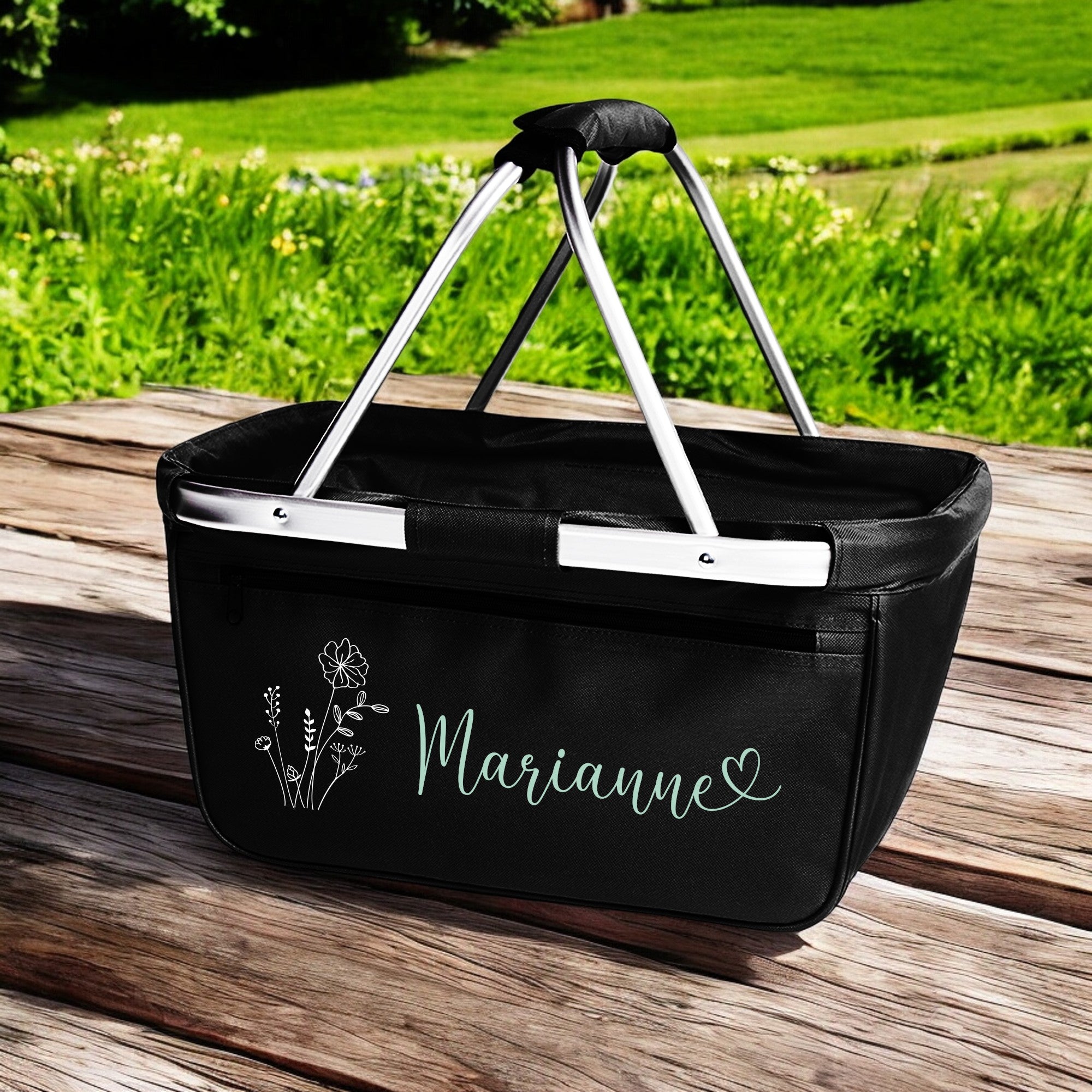 Einkaufskorb schwarz mit Name Marianne und Blumenmotiv auf Holzbrett im Garten