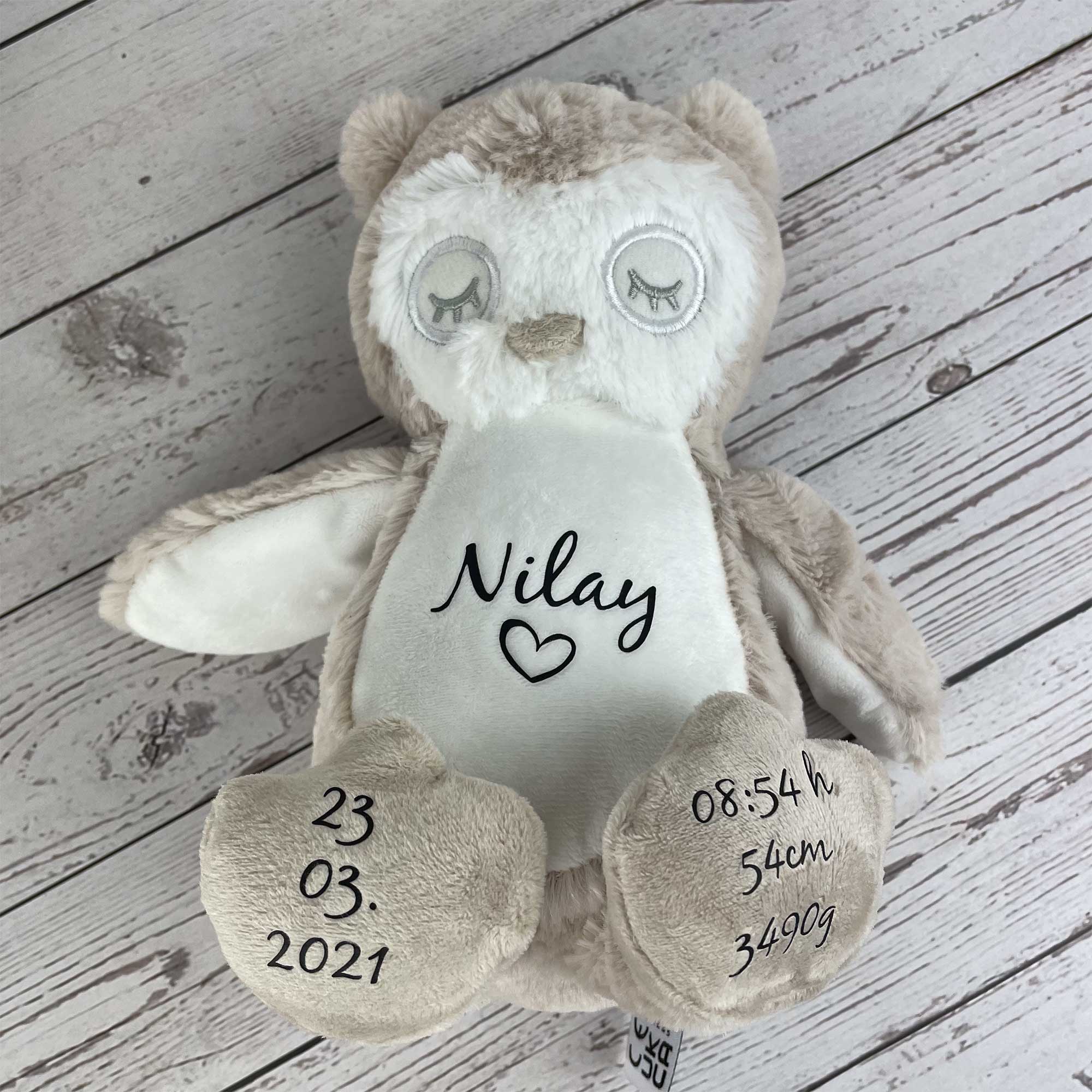 Personalisierte Eule mit Name Nilay und detaillierten Geburtsdaten – auf weichem Holzhintergrund liegend