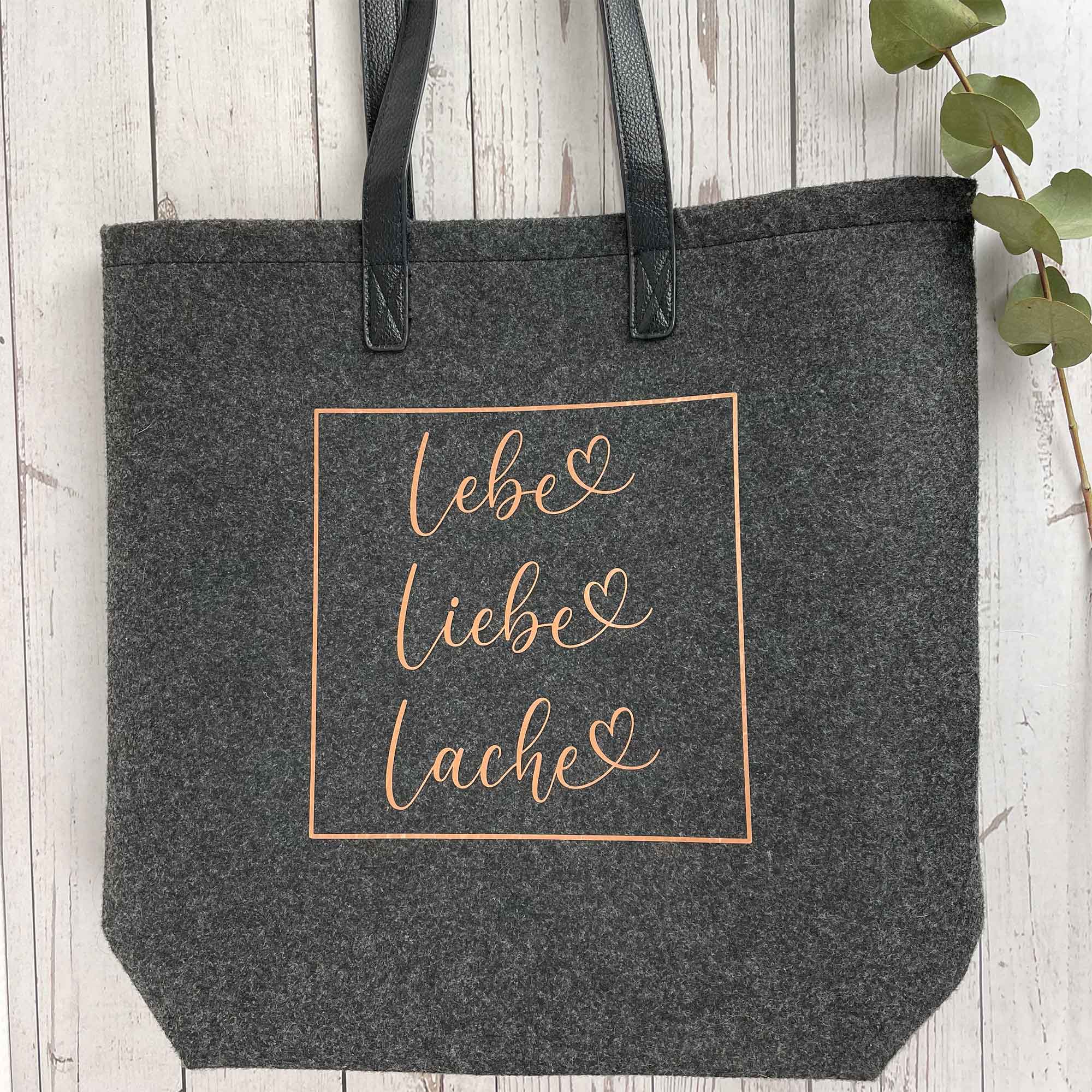 Lebe Liebe Lache Filztasche liegend auf Holzuntergrund – Filztasche mit Motiv als Geschenk