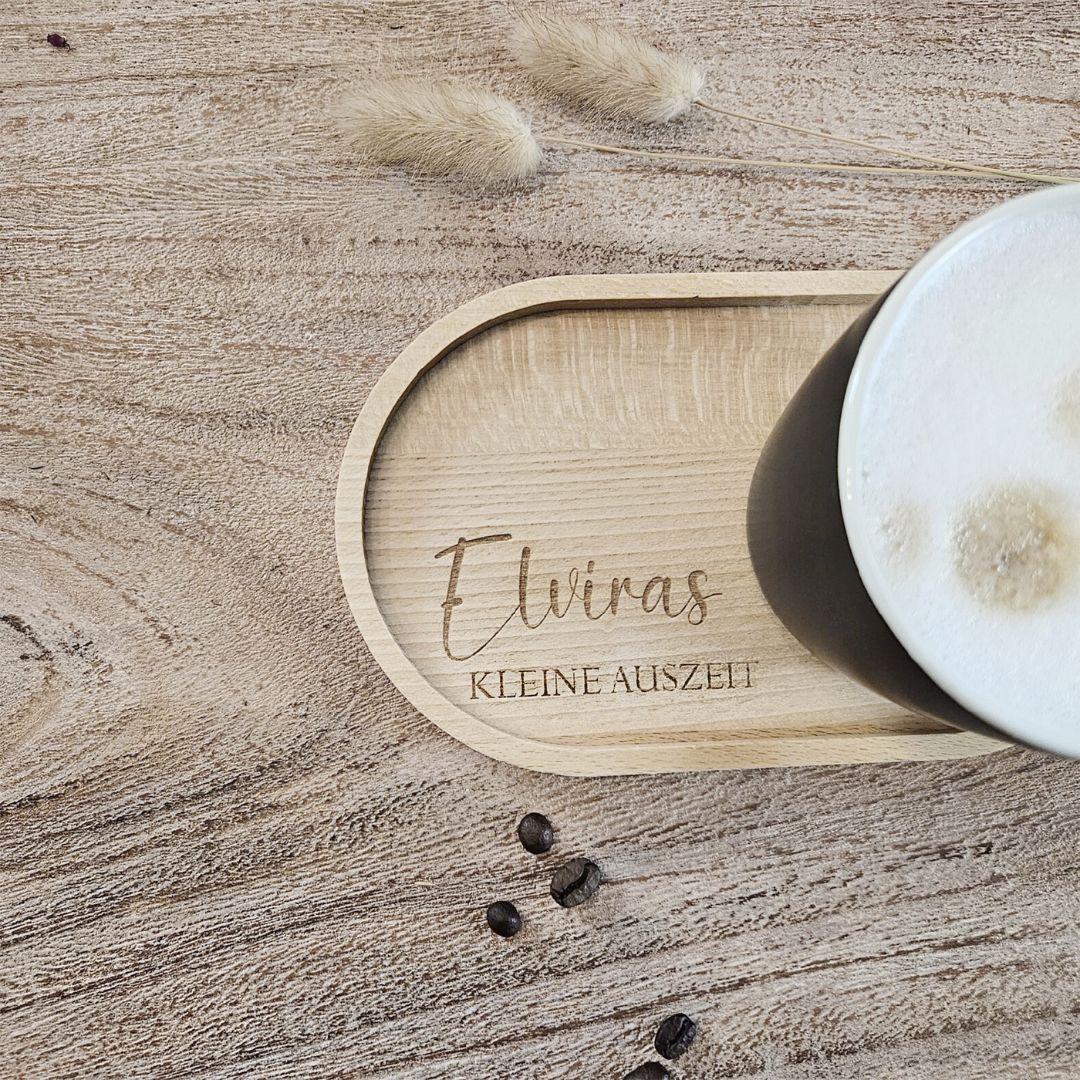 Tablett mit Gravur 'kleine Auszeit' und schwarzer Tasse, von oben fotografiert mit Kaffeebohnen