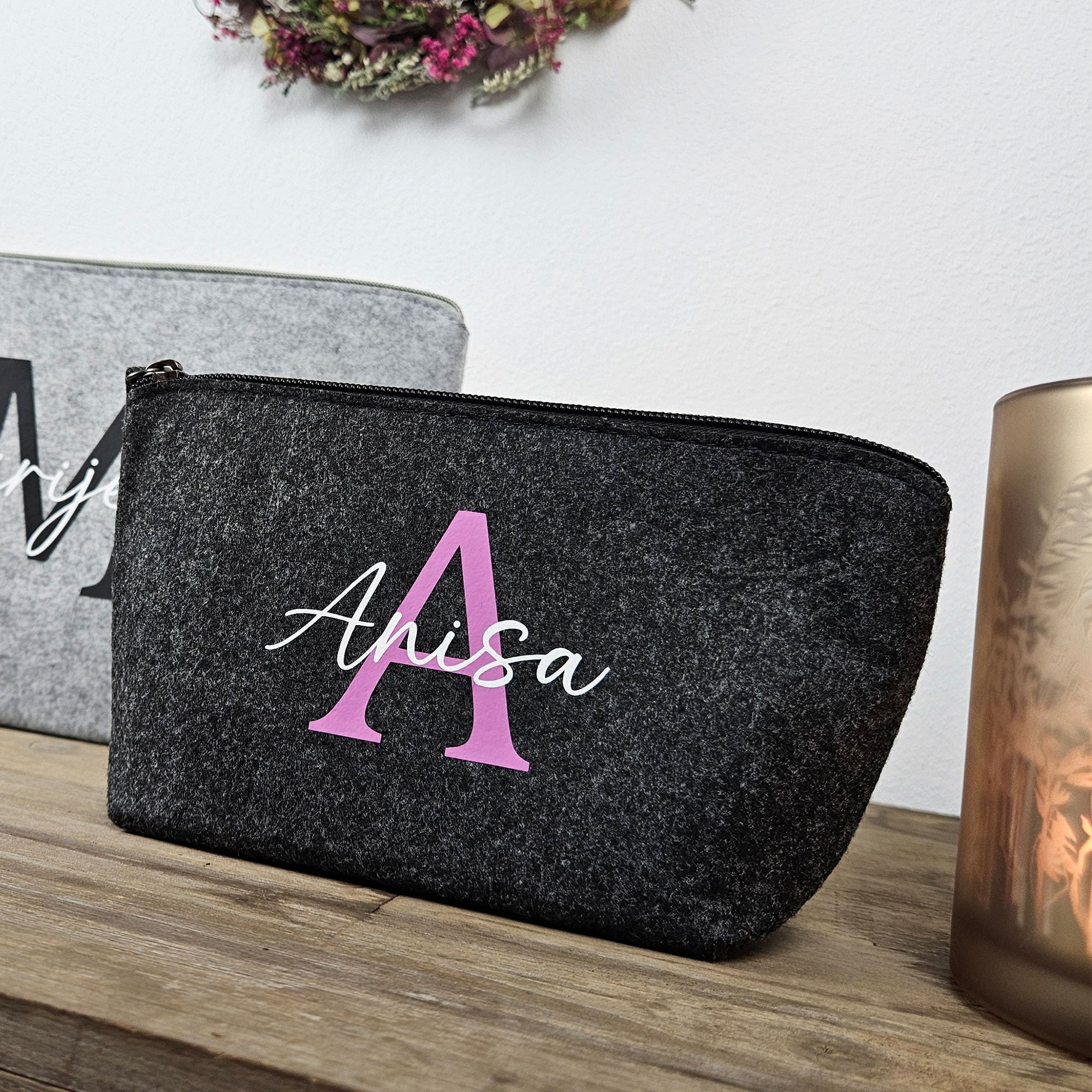 Kosmetiktasche aus Filz in Anthrazit auf Holzkiste – personalisiertes Geschenk für Frauen.