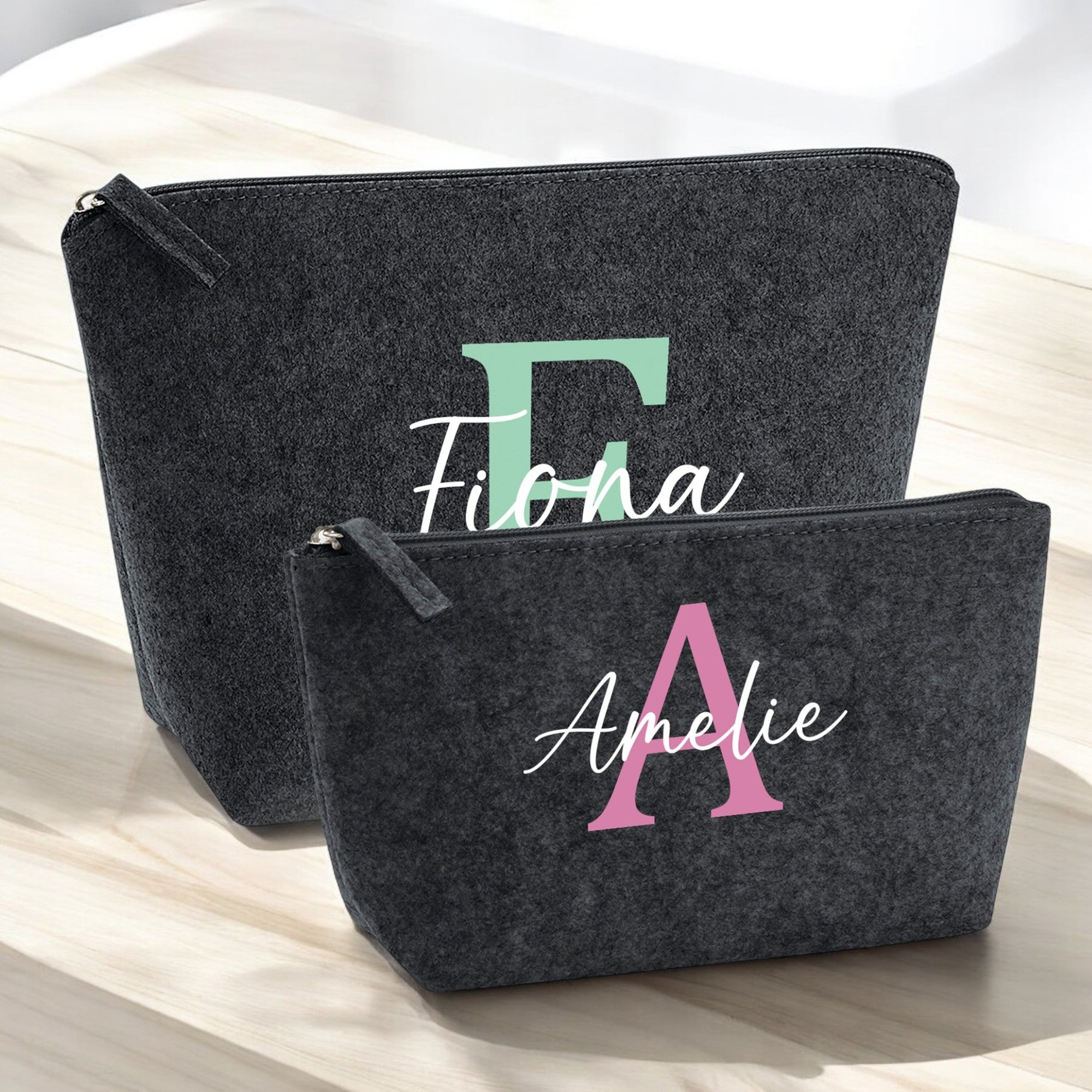 Set aus zwei personalisierten Kosmetiktaschen aus Filz in Anthrazit auf Holztisch