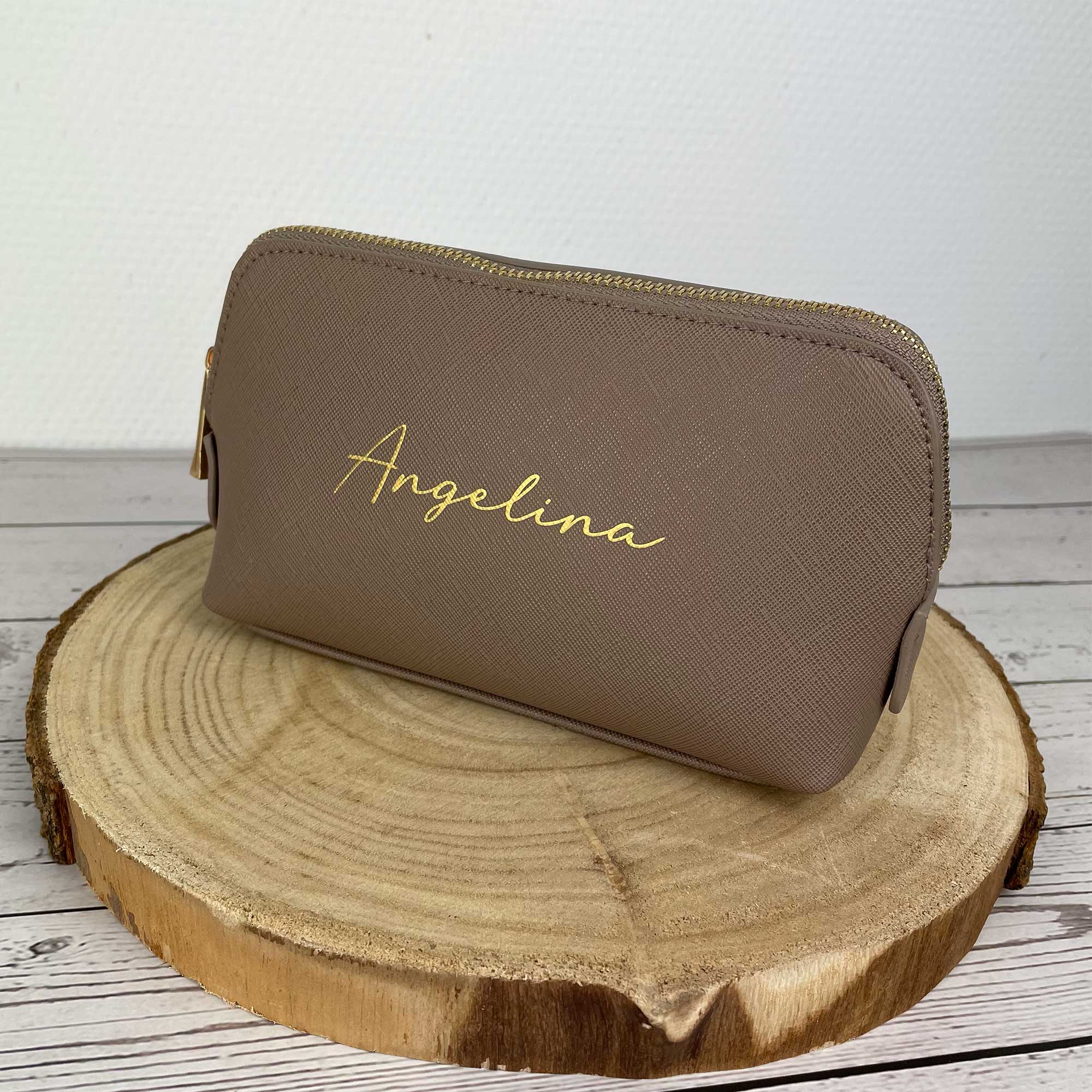 Personalisierte Kosmetiktasche in Taupe mit goldenem Namen auf Holzscheibe
