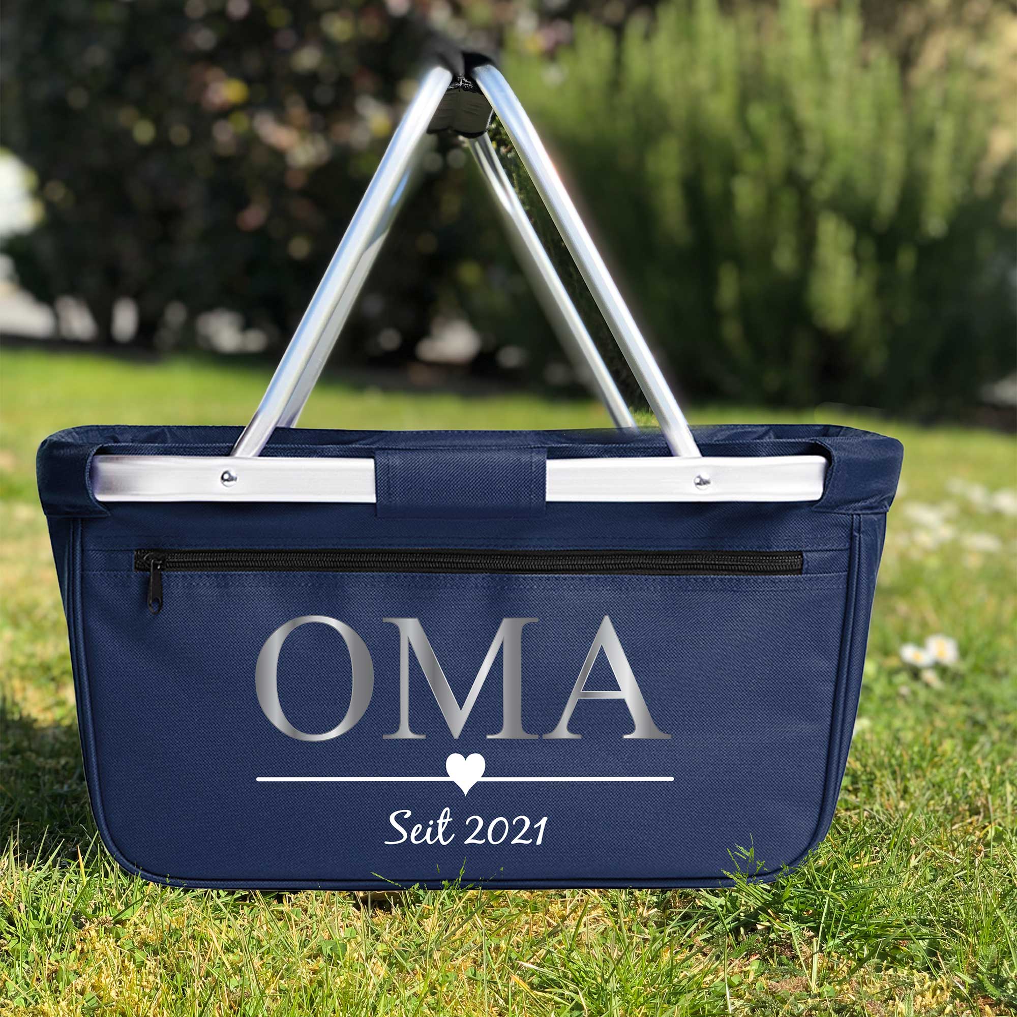 Blauer Einkaufskorb personalisiert mit 'Oma' und Jahreszahl auf einer Wiese