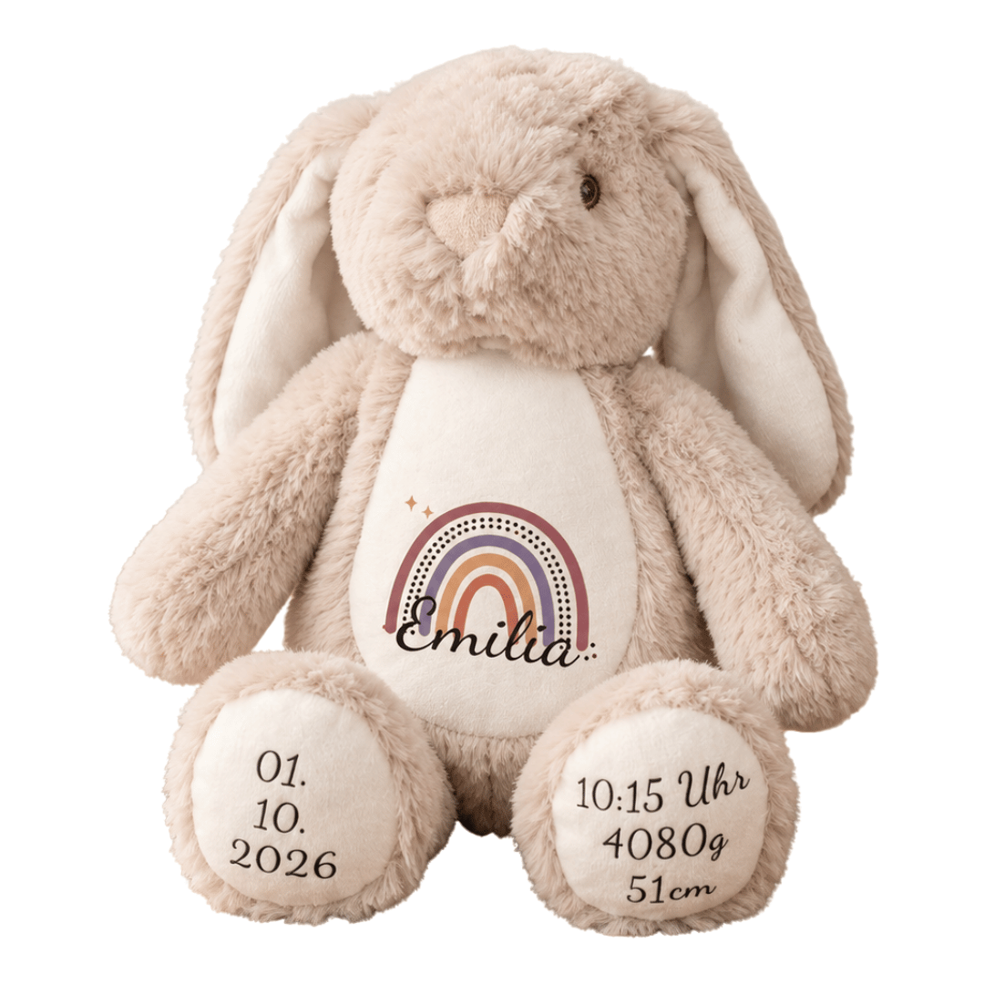 Beiger Kuschelhase mit dem Namen Emilia und einem Regenbogen in Rosa-, Beige- und Naturtönen auf dem weißen Bauch.