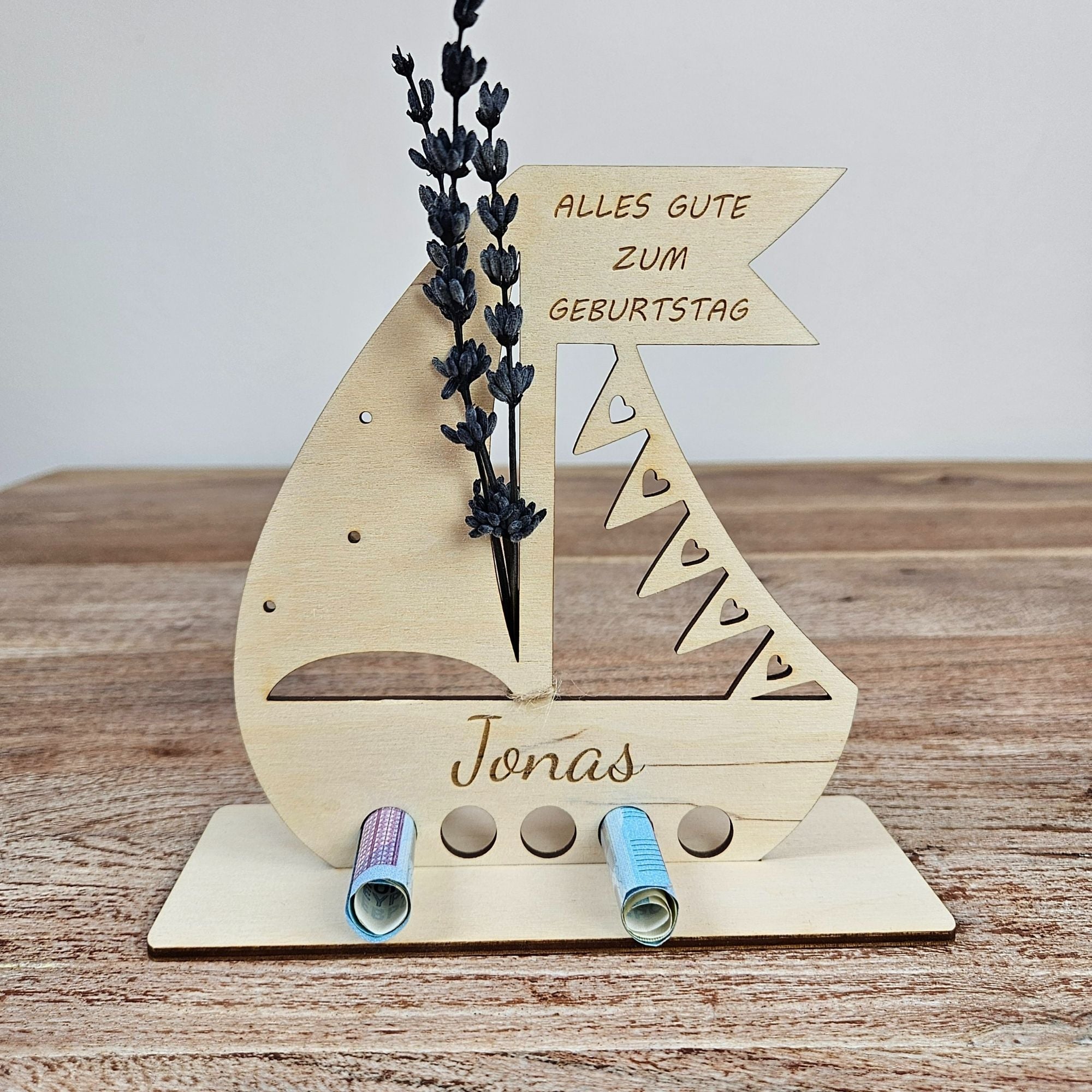 Geldgeschenk aus Holz zum Geburtstag, Segelboot mit Gravur und personalisiertem Namen auf Holztisch